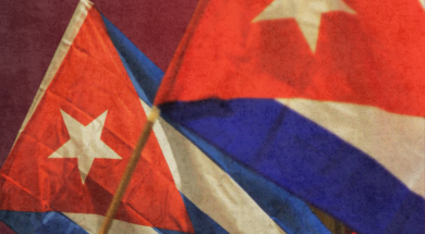 A imagem mostra duas bandeiras de Cuba tremulando em destaque, com seus icônicos tons de vermelho, branco e azul.
