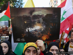 A imagem retrata manifestantes no Líbano segurando bandeiras da Palestina e do Líbano, além de cartazes que denunciam os bombardeios em Gaza e expressam solidariedade ao povo palestino. No centro, um cartaz com uma imagem de destruição exibe a palavra em árabe "resistência" sobre uma área devastada por bombardeios. O contexto remete à contínua ofensiva israelense e ao apoio internacional à causa palestina. A manifestação ilustra a indignação e o apoio dos libaneses à resistência palestina em meio ao conflito. Foto: Mohamed Azakir/Reuters.