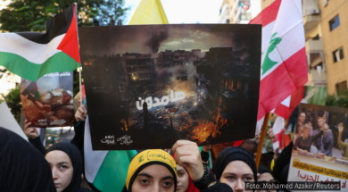 A imagem retrata manifestantes no Líbano segurando bandeiras da Palestina e do Líbano, além de cartazes que denunciam os bombardeios em Gaza e expressam solidariedade ao povo palestino. No centro, um cartaz com uma imagem de destruição exibe a palavra em árabe "resistência" sobre uma área devastada por bombardeios. O contexto remete à contínua ofensiva israelense e ao apoio internacional à causa palestina. A manifestação ilustra a indignação e o apoio dos libaneses à resistência palestina em meio ao conflito. Foto: Mohamed Azakir/Reuters.