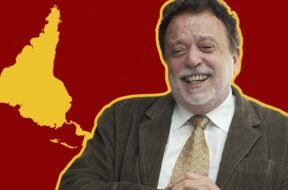 Fotografia de Theotônio dos Santos sorrindo, vestindo terno e gravata, com um mapa da América Latina invertido em relação à cartografia eurocêntrica. O mapa está em amarelo sobre um fundo vermelho listrado.