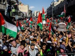 Protesto com uma multidão levantando bandeiras da Palestina em apoio à causa palestina.