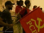 Grupo de jovens militantes da UJC no Piauí em ato público, com uma bandeira vermelha do PCB em destaque, em ambiente ao ar livre.