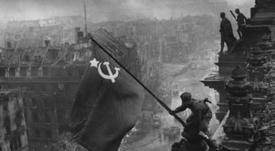 Foto preto e branco que retrata soldado soviético balançando bandeira da URSS na Berlim conquistada, no dia 9 de maio, marcando o dia que ficaria conhecido como Dia da Vitória