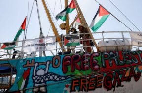 Imagem mostra ativistas a bordo de um barco com bandeiras da Palestina, murais com a frase “Free Gaza” e faixas de apoio às crianças de Gaza. A embarcação fazia parte da flotilha humanitária rumo à Faixa de Gaza.