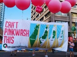 Foto de manifestação com balões rosas e uma grande faixa escrito "Não tem como fazer pinkwash disso", do movimento Queers contra o Apartheid Israelense.