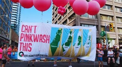 Foto de manifestação com balões rosas e uma grande faixa escrito "Não tem como fazer pinkwash disso", do movimento Queers contra o Apartheid Israelense.