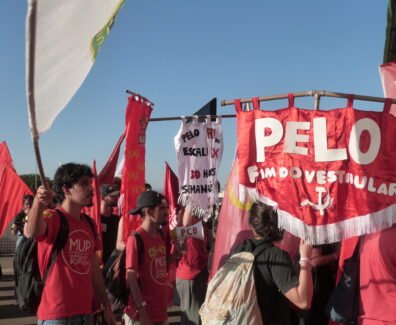 Grupo de estudantes em manifestação ao ar livre, vestindo camisetas vermelhas e segurando bandeiras e faixas; uma delas diz “Pelo fim do vestibular”, enquanto outras defendem pautas como Universidade Popular e melhores condições de estudo. Foto: Amanda Braun / UJC Brasil.